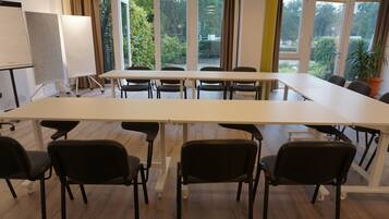 A conference room with a large table, black chairs, and a whiteboard.