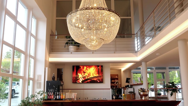 Un vestíbulo espacioso con una gran lámpara de araña, zona de bar y un amplio ventanal con vistas al exterior.