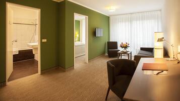Una habitación de hotel con baño, zona de estar con mesa y sillas, y una cama.