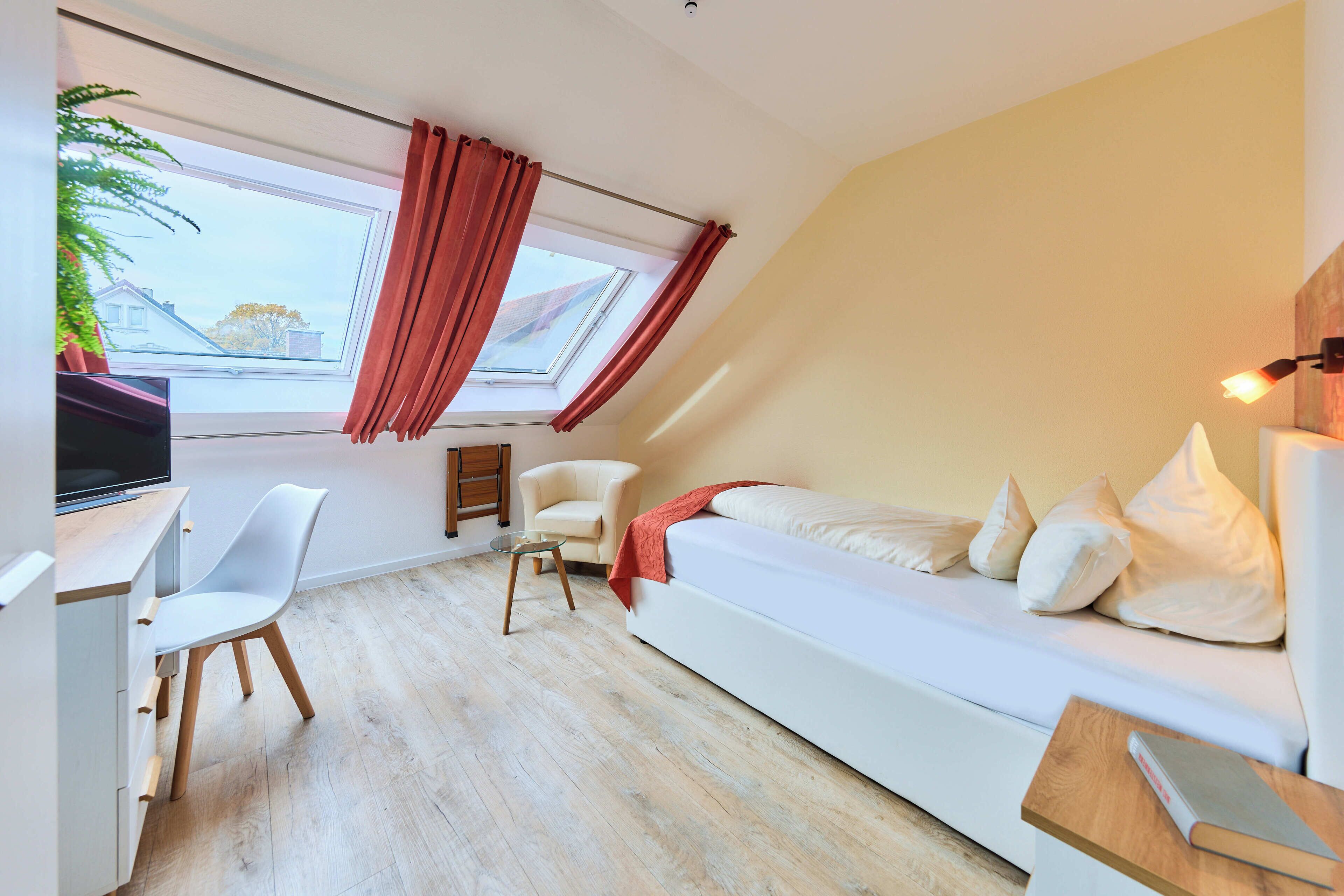 A modern bedroom with a skylight, a sofa, a desk, and a chair.