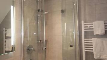 A modern bathroom with a glass-enclosed shower, a white sink, and a towel rack.