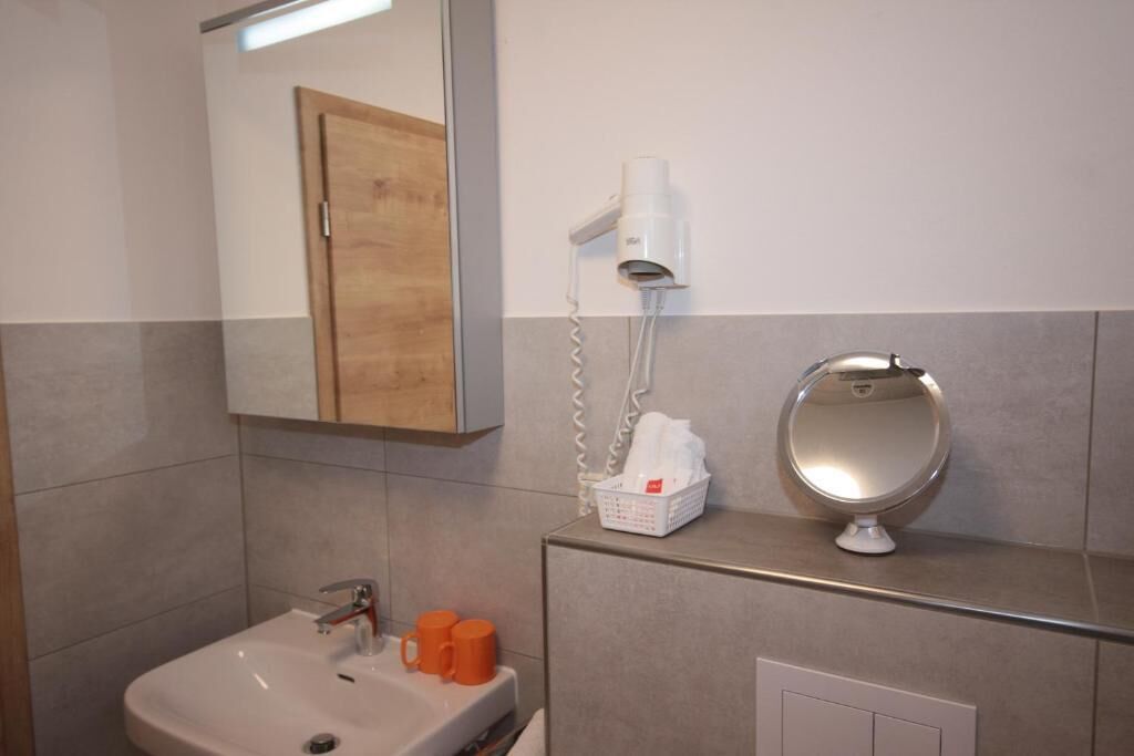 Une salle de bain équipée d’un lavabo, d’un miroir, d’un sèche-cheveux et d’un panier contenant des articles de toilette.