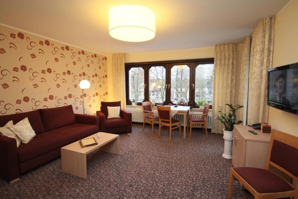 Een woonkamer met een bank, stoelen, een salontafel, een eettafel en een televisie.
