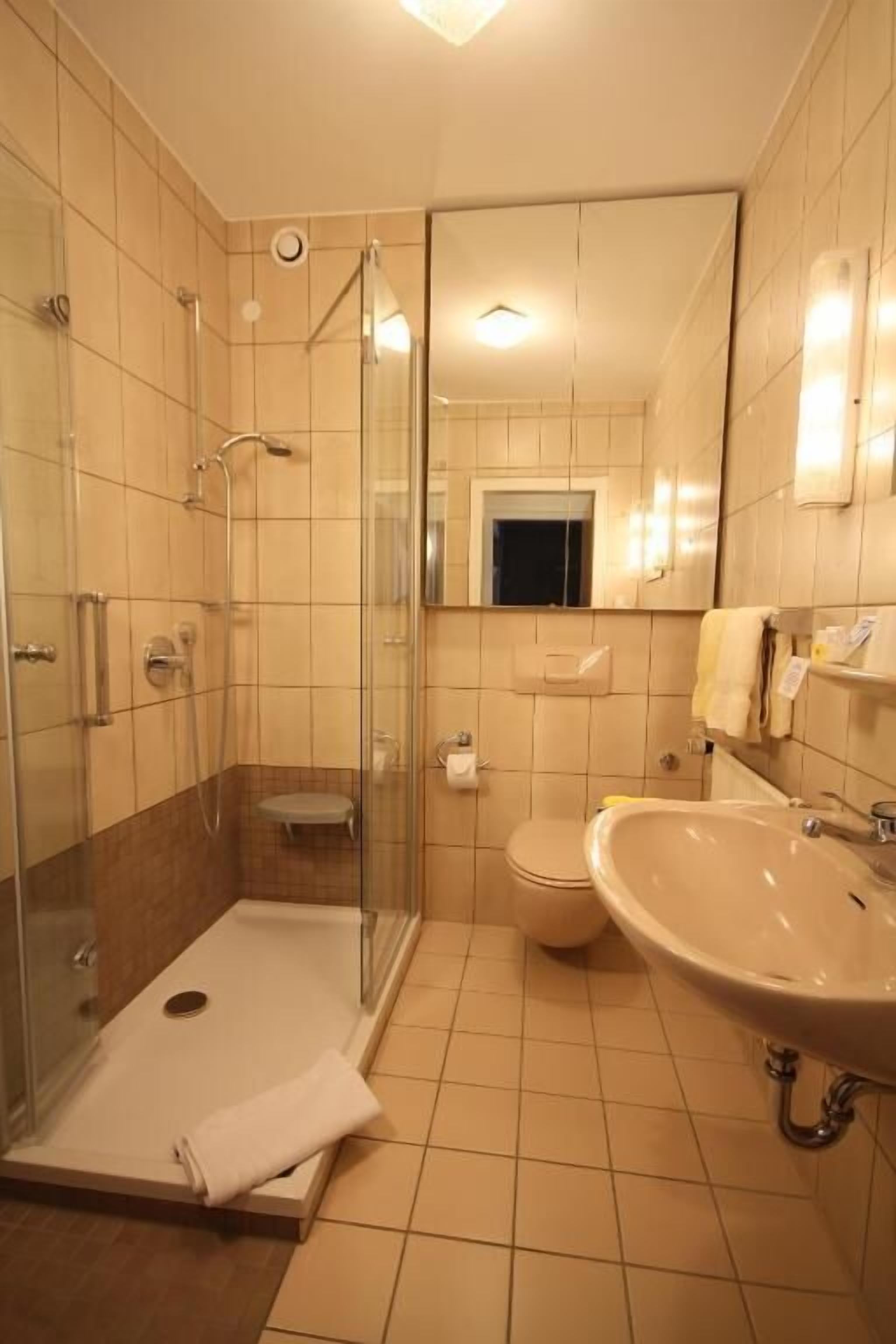 Un bagno con doccia vetrata, un water e un lavandino.