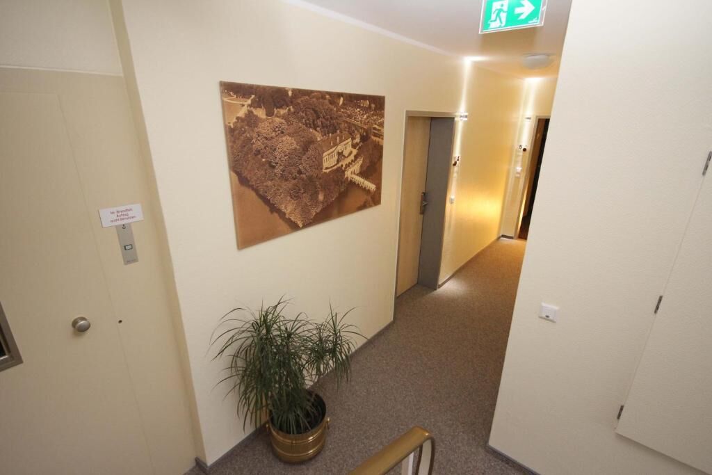 A hallway with a large historical map, a potted plant, and an emergency exit sign.