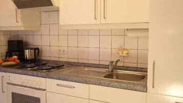 A kitchen with white cabinets, a stainless steel sink, a coffee maker, and a microwave.