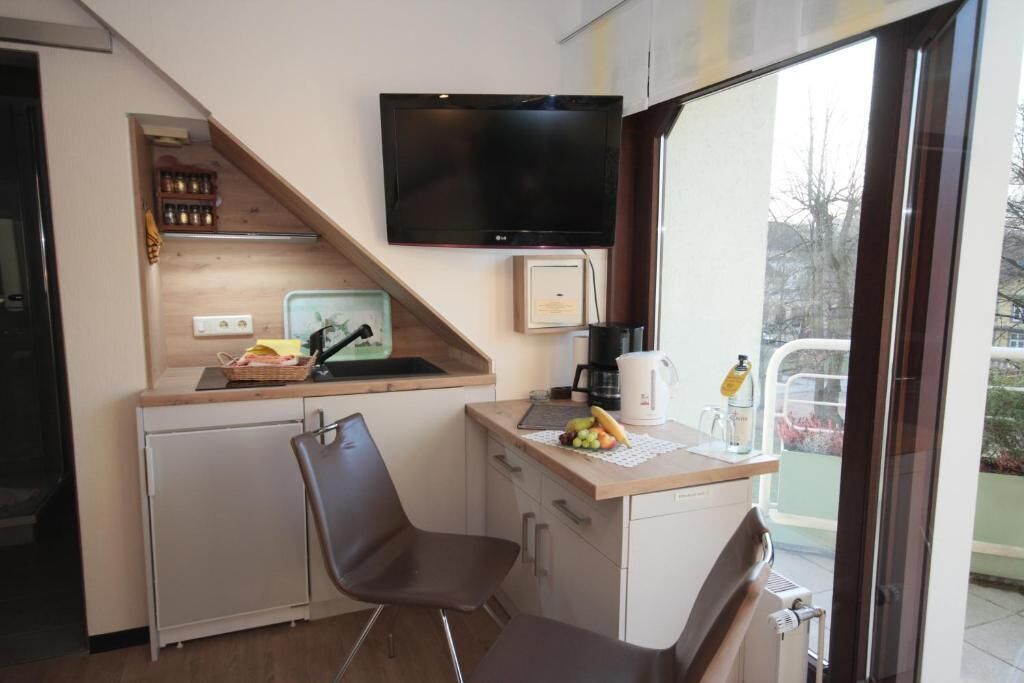 Eine kleine Küche mit Flachbildfernseher, Kaffeemaschine und Obstschale auf der Arbeitsfläche.
