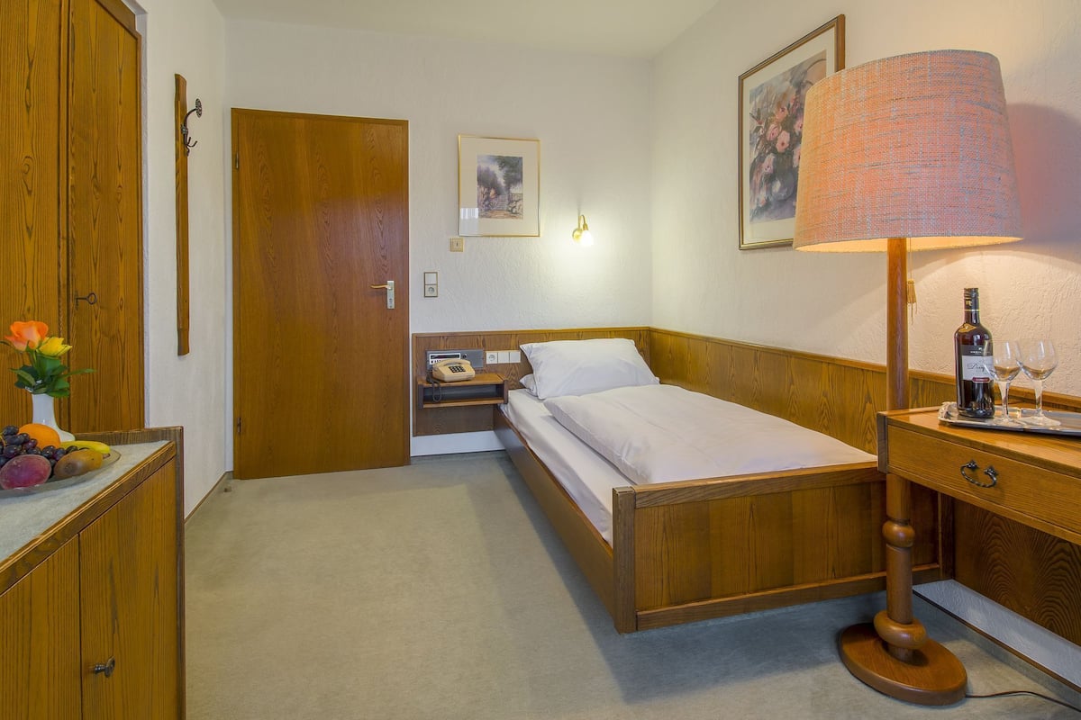 Ein Schlafzimmer mit einem hölzernen Bett, einem Nachttisch, einer Lampe und einer Obstschale auf der Kommode.