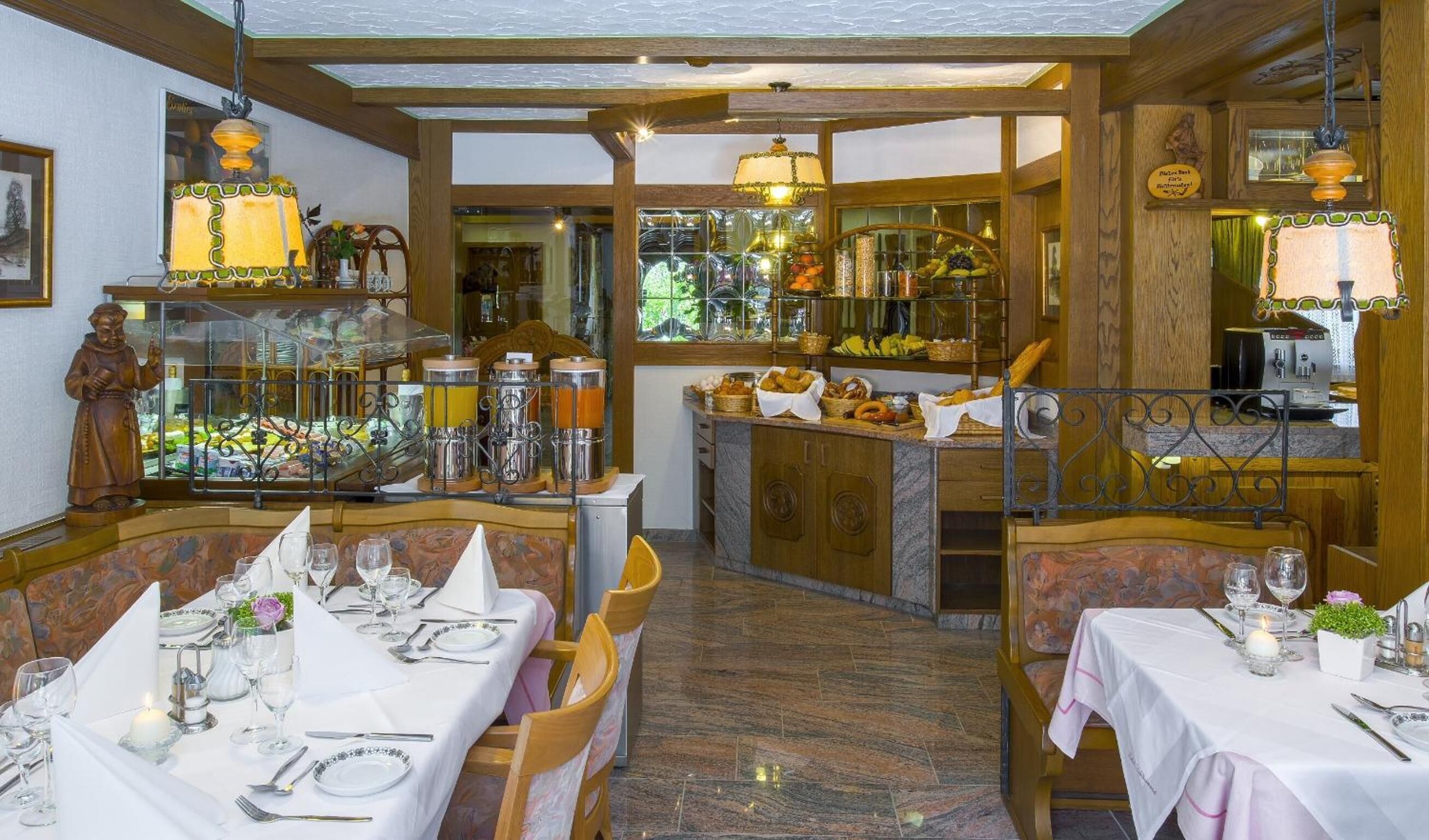 Ein Restaurant mit mehreren gedeckten Tischen für Gäste, verschiedenen Speisen- und Getränkeauslagen und einer einladenden, gemütlichen Atmosphäre.