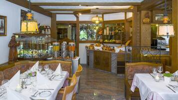 Un restaurante con varias mesas dispuestas para comensales, una variedad de exhibiciones de comida y bebidas, y un ambiente cálido y acogedor.