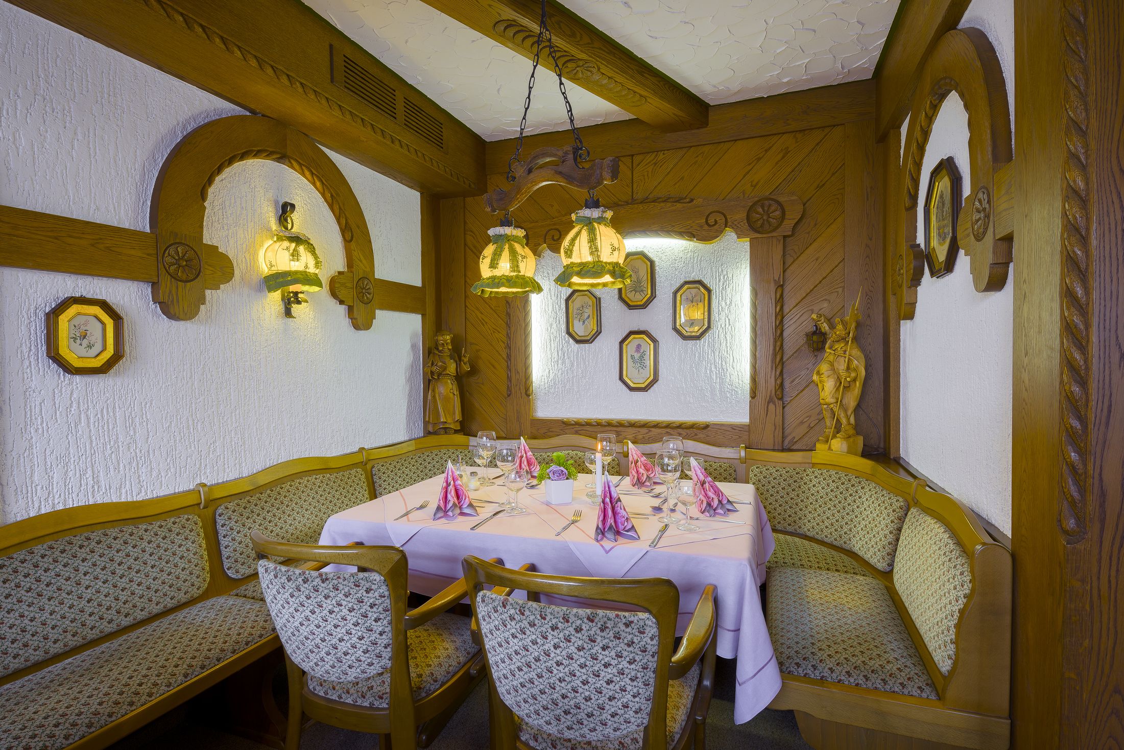 Un comedor con un banco de madera para sentarse, una mesa preparada para una comida y apliques decorativos en la pared.