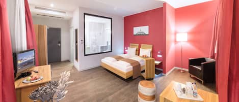 A modern hotel room with a bed, desk, TV, and a city view.