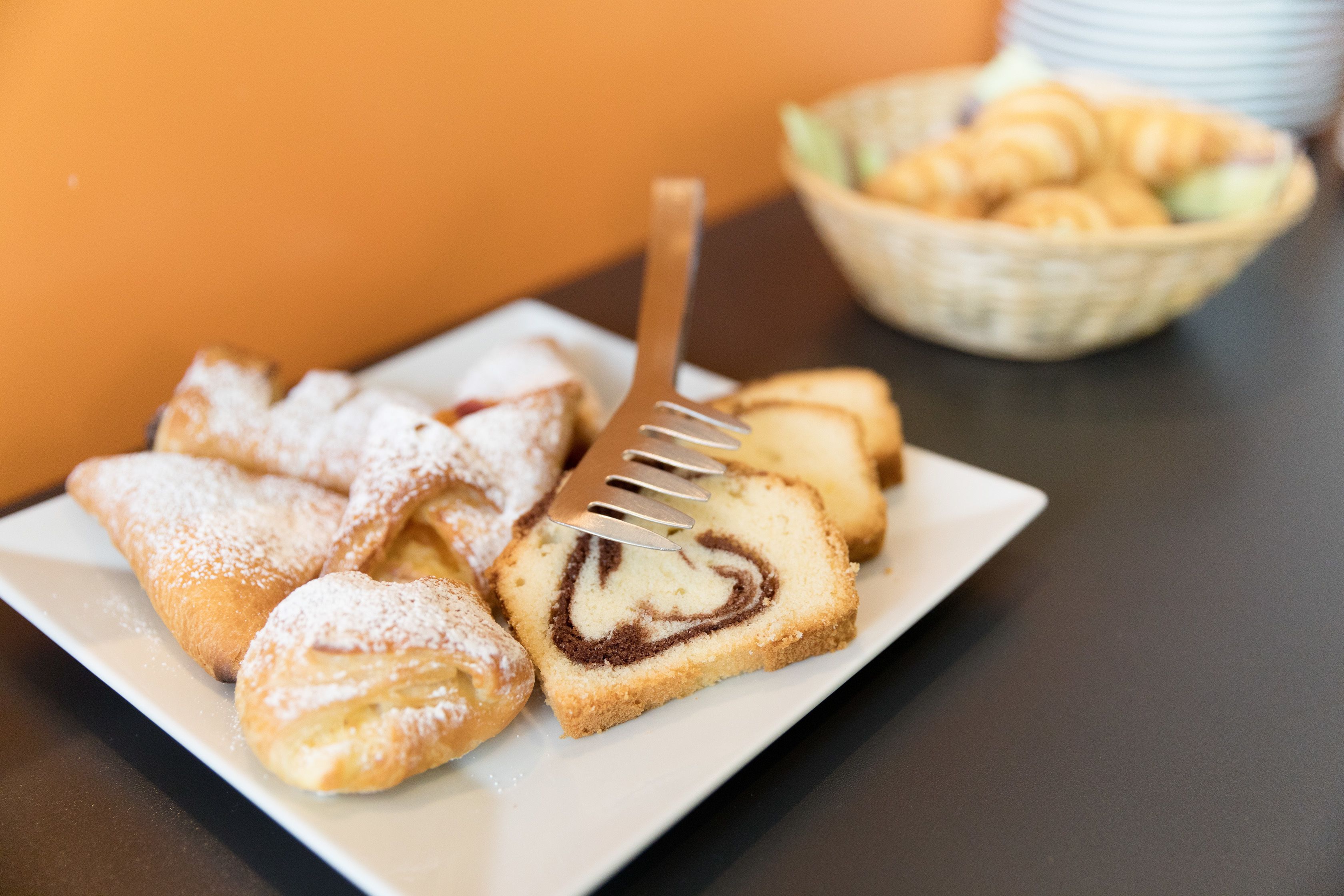 Un plato de pasteles que incluye una rebanada con relleno en forma de corazón, espolvoreado con azúcar glas y un tenedor.