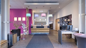A modern reception area with a wooden desk, a reception counter, and a 'Welcome' sign. - AMH Airport-Messe-Hotel (Filderstadt)