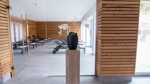 A modern interior with wooden paneling, a reception desk, lounge area with chairs and tables, and a large potted plant. - BSW - Erlebnishotel Festenburg (Clausthal-Zellerfeld)