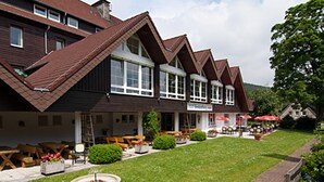 A row of chalet-style buildings with a covered outdoor seating area and a small garden. - BSW - Erlebnishotel Festenburg (Clausthal-Zellerfeld)