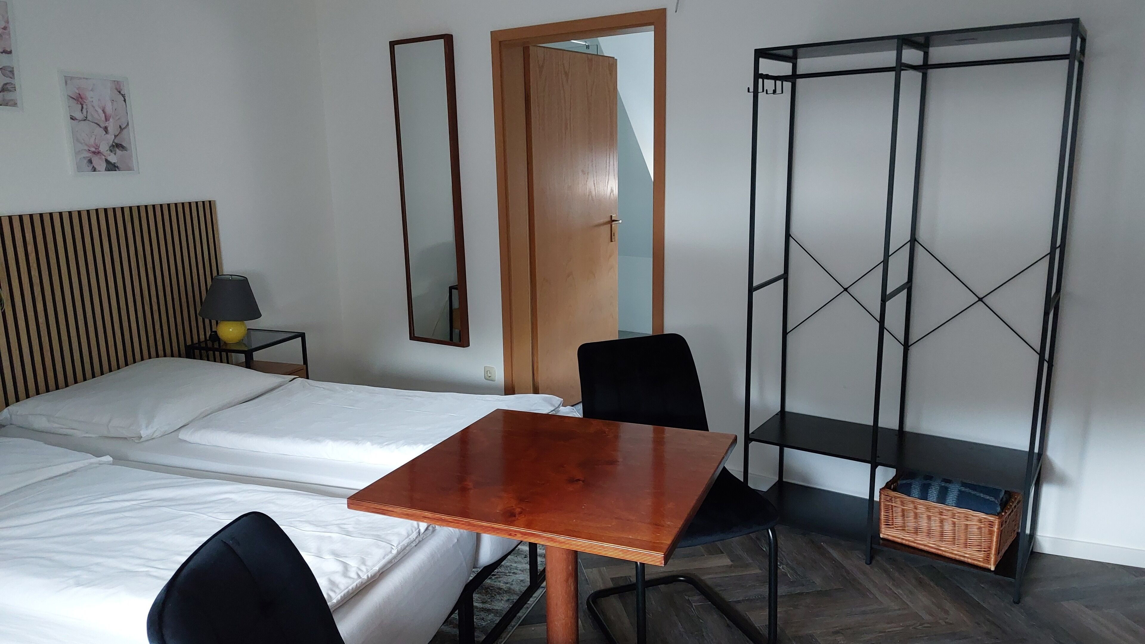 Een kamer met een bed, een tafel, een stoel, een kledingkast en een spiegel.