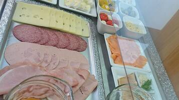 A buffet spread with various food items including meats, cheeses, fruits, and beverages.