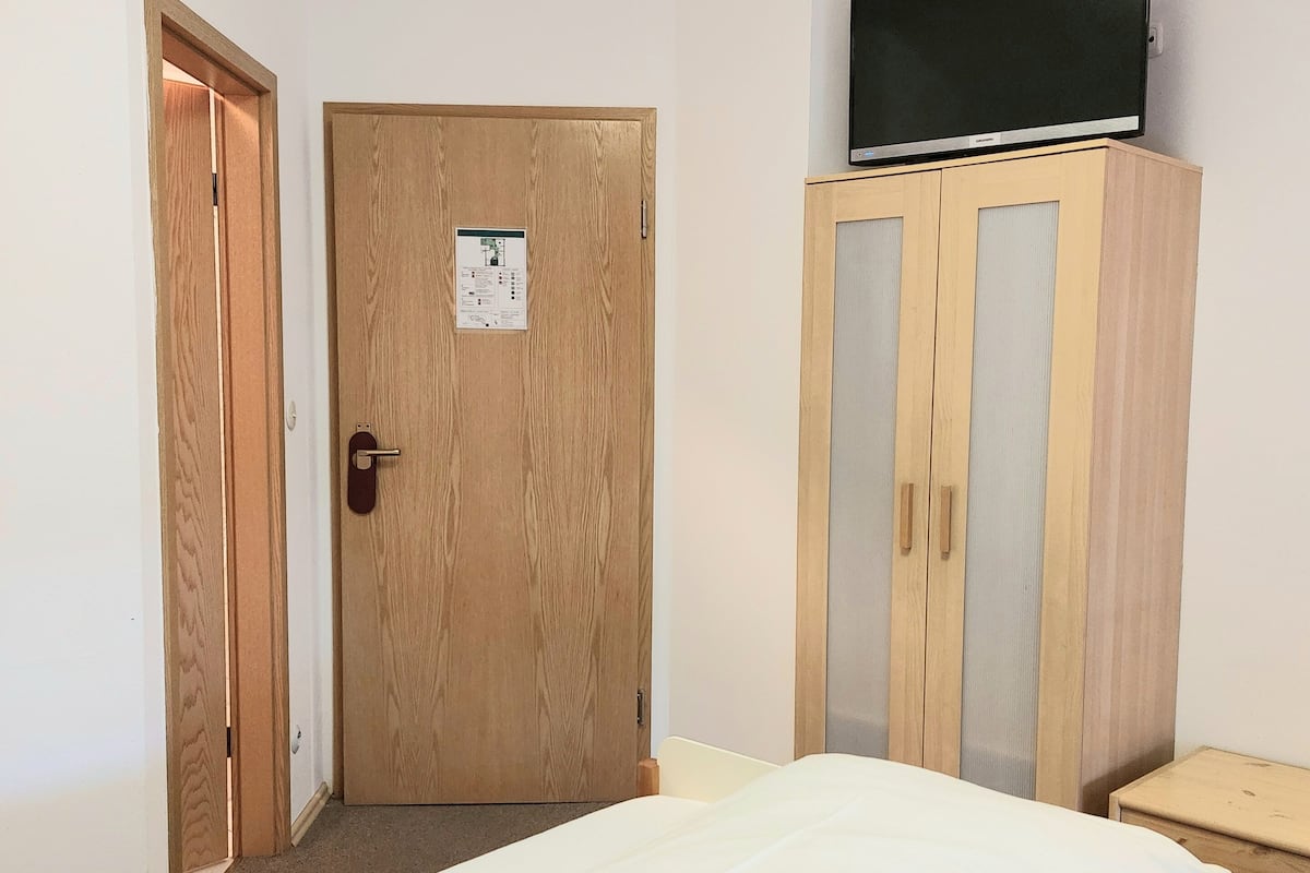 Ein Hotelzimmer mit einem Bett, einem Holzschrank, einem Fernseher auf dem Schrank und einer Tür mit einem Hinweisschild.