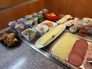 A buffet table with various food items including yogurt, fish, cheese, and bread. - Gästehaus Langhammer (Bubenreuth)