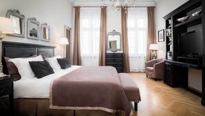 A spacious bedroom with a large bed, a dresser, a television, and a chandelier. - Palacina Berlin Apartments (Berlin)