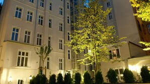 A multi-story hotel with a central courtyard featuring a large tree. - Palacina Berlin Apartments (Berlin)