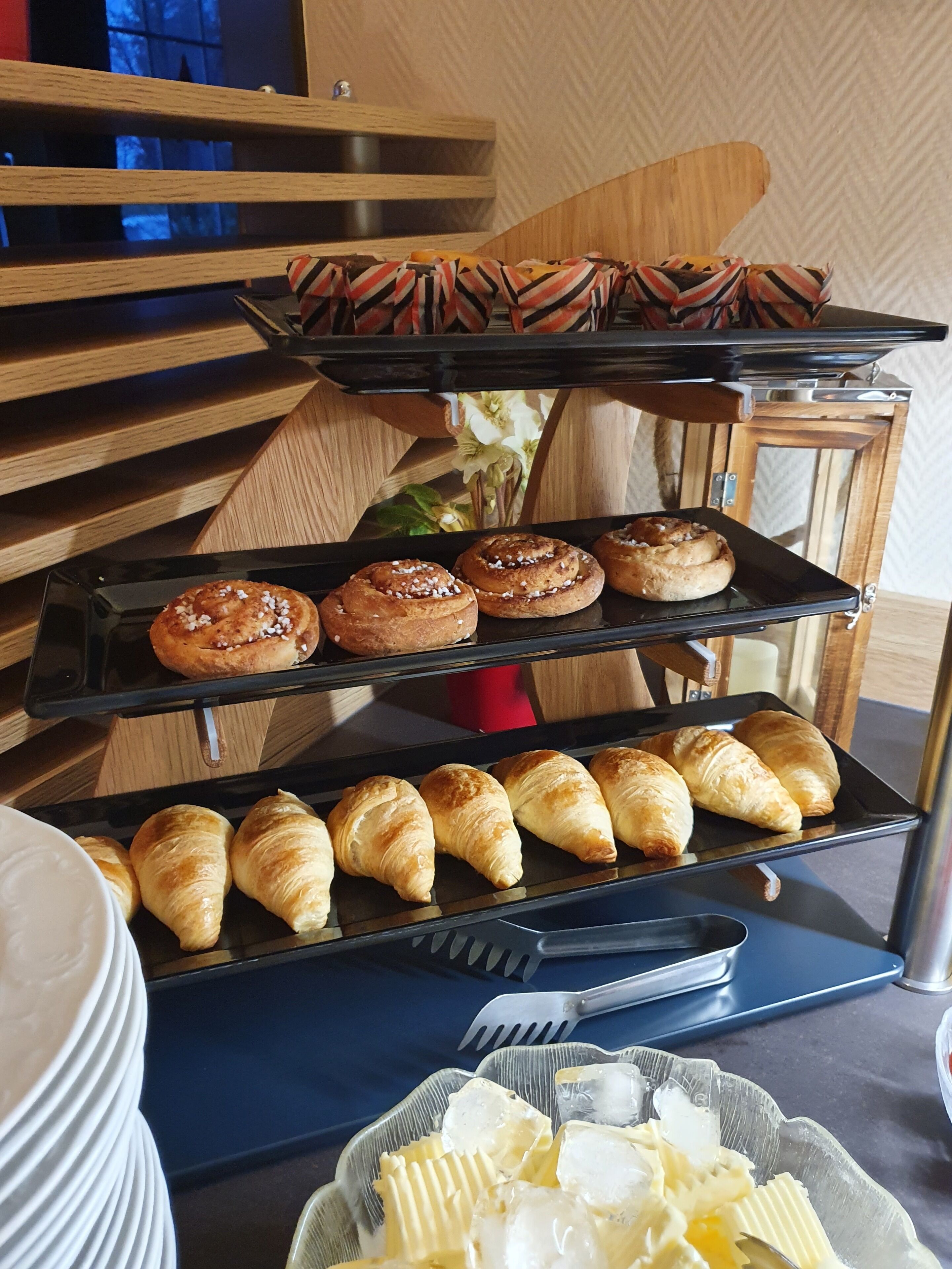 A display of pastries including croissants and cinnamon rolls on a tiered serving tray.