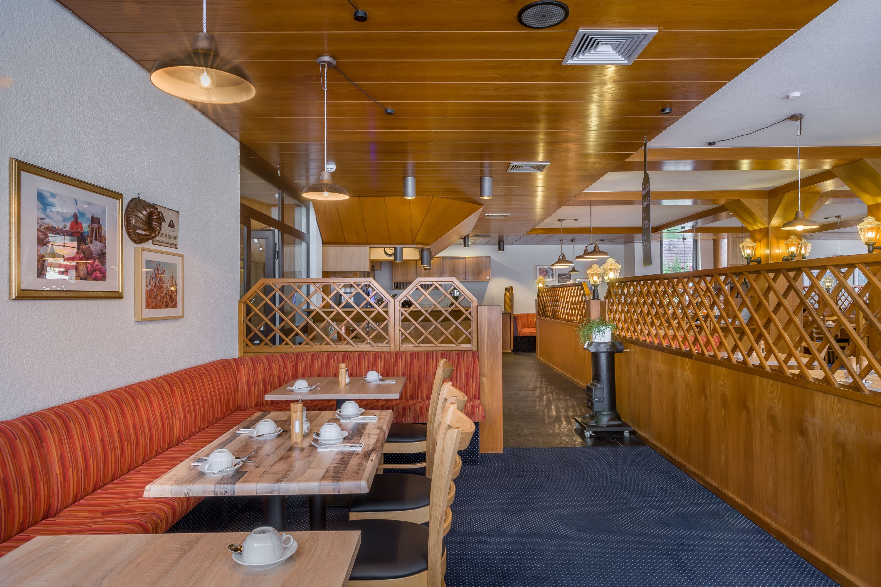 Un interior de restaurante con cabinas de madera, mesas y lámparas colgantes.