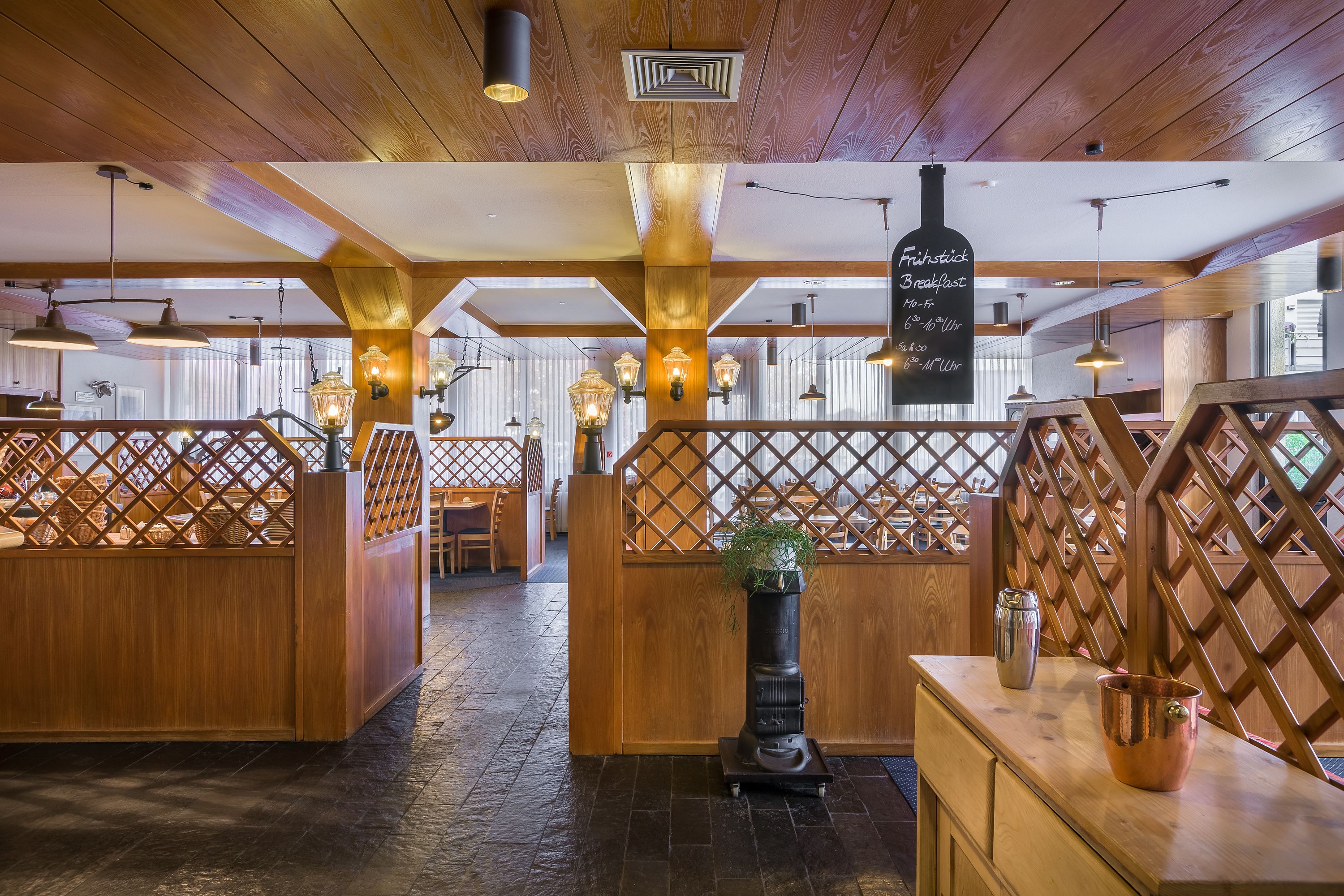 L’intérieur d’un restaurant, avec des poutres en bois, des cloisons ajourées et des luminaires suspendus.