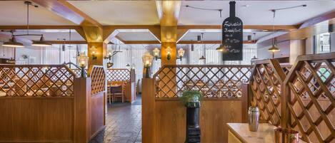 L’intérieur d’un restaurant, avec des poutres en bois, des cloisons ajourées et des luminaires suspendus.