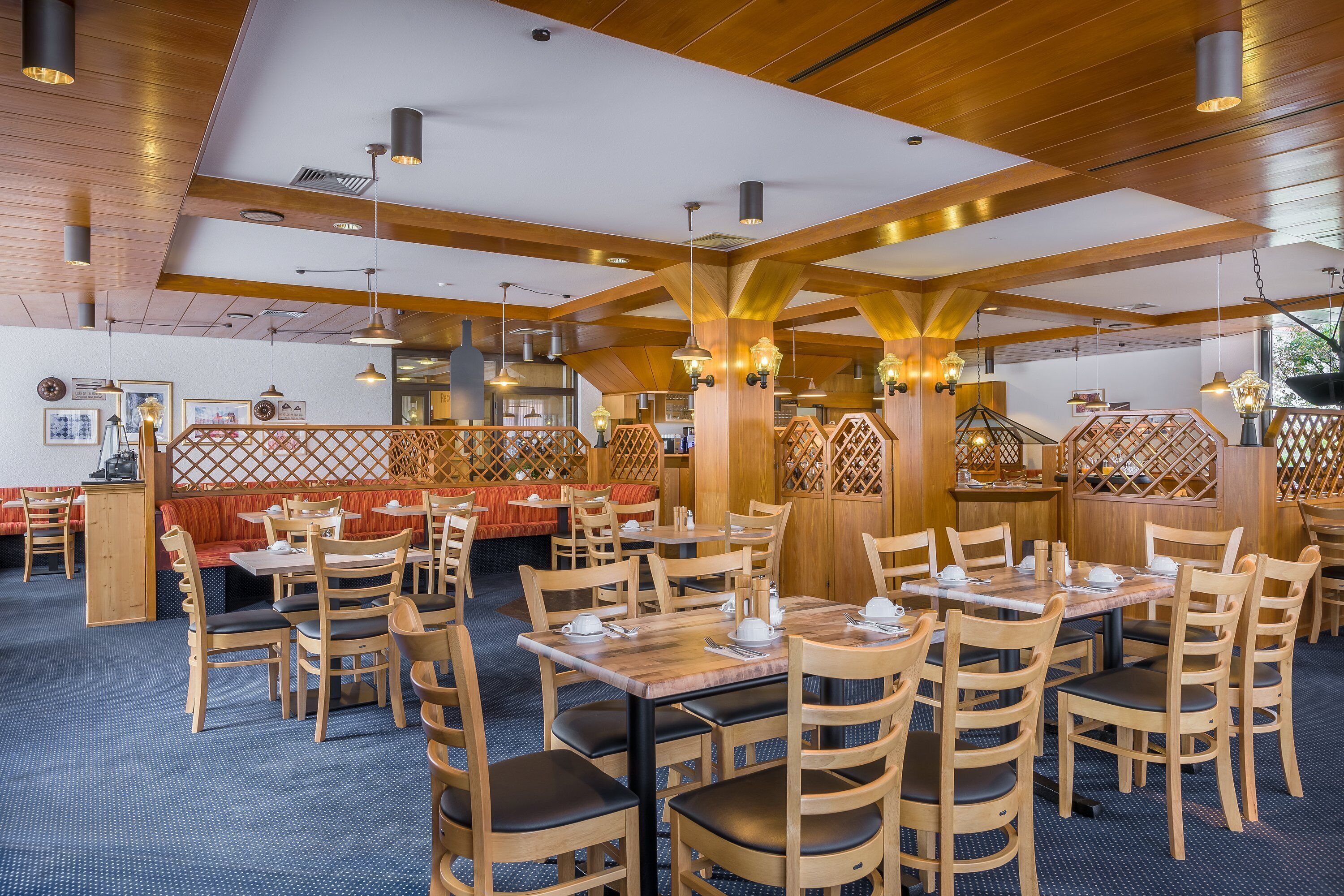 A restaurant with wooden furniture, high ceilings, and pendant lighting.