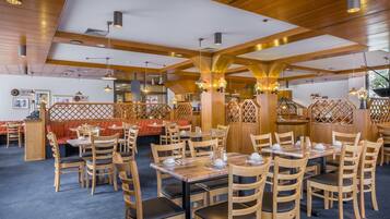 A restaurant with wooden furniture, high ceilings, and pendant lighting.