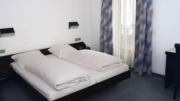 A hotel room with a single bed, a bedside table, a nightstand, and a window with curtains. - Hotel Gasthof Traube (Kernen)