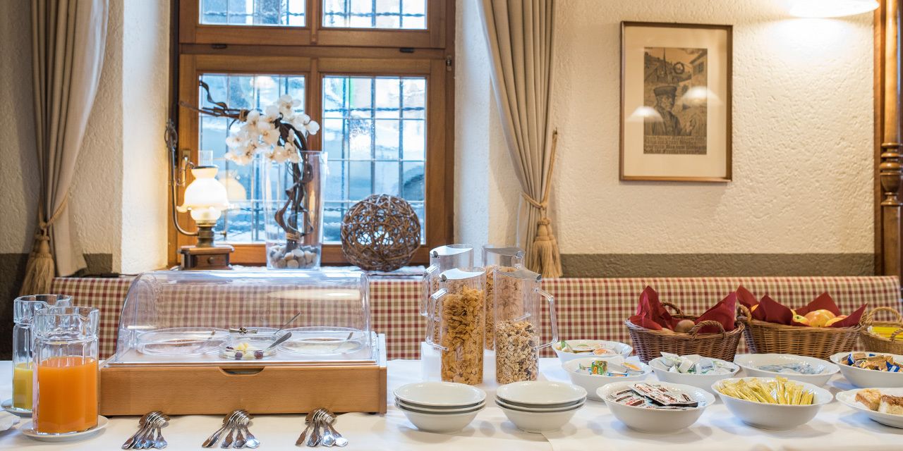 A breakfast buffet setup with various food items and a fruit juice dispenser.