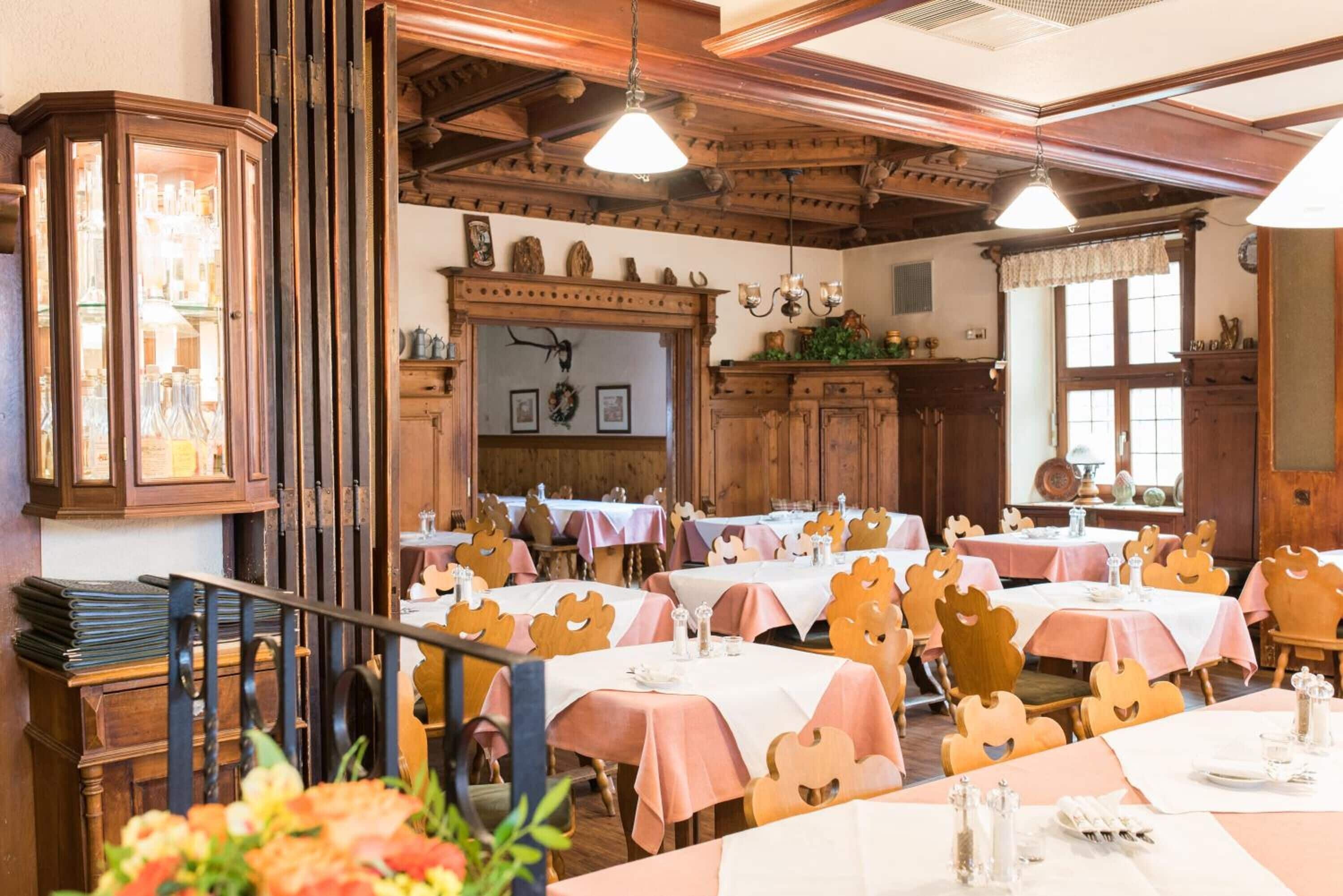 Un restaurante con muebles de madera, mesas con manteles rosas y un ambiente rústico.