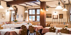 A dining area with tables set for a meal, wooden chairs, and hanging pendant lights. - Hotel Zum Specht (Hoesbach)