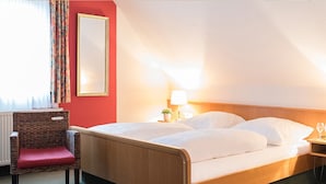 A hotel room with a bed, a chair, a nightstand, and a mirror. - Hotel Zum Specht (Hoesbach)