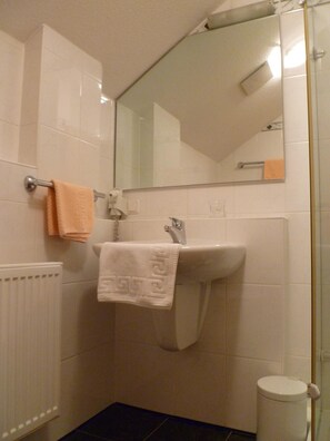 A bathroom with a white sink, a mirror, and a toilet. - Hotel Zum Specht (Hoesbach)