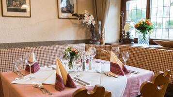 Un espace repas avec des nappes à carreaux, des tables soigneusement dressées avec des verres à vin, des couverts et des centres de table floraux.