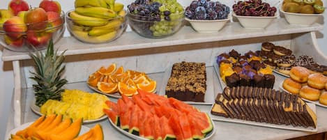 A buffet table with various fruits and desserts.
