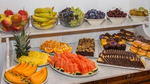 Una mesa de buffet con diversas frutas y postres.