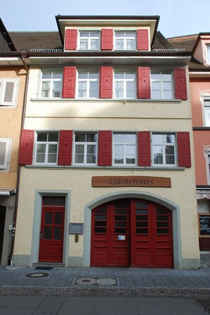 Un edificio de dos pisos con contraventanas rojas y un letrero que dice 