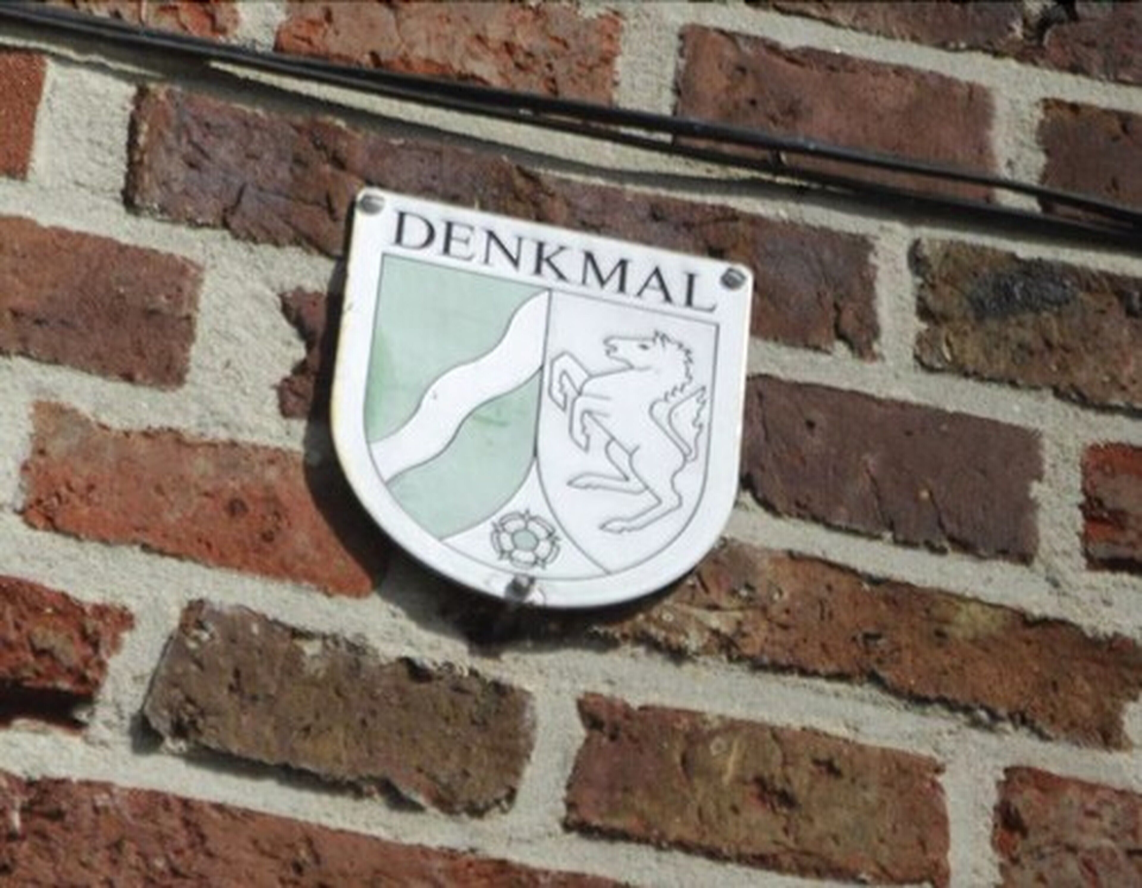 A DENKMAL sign on a brick wall.