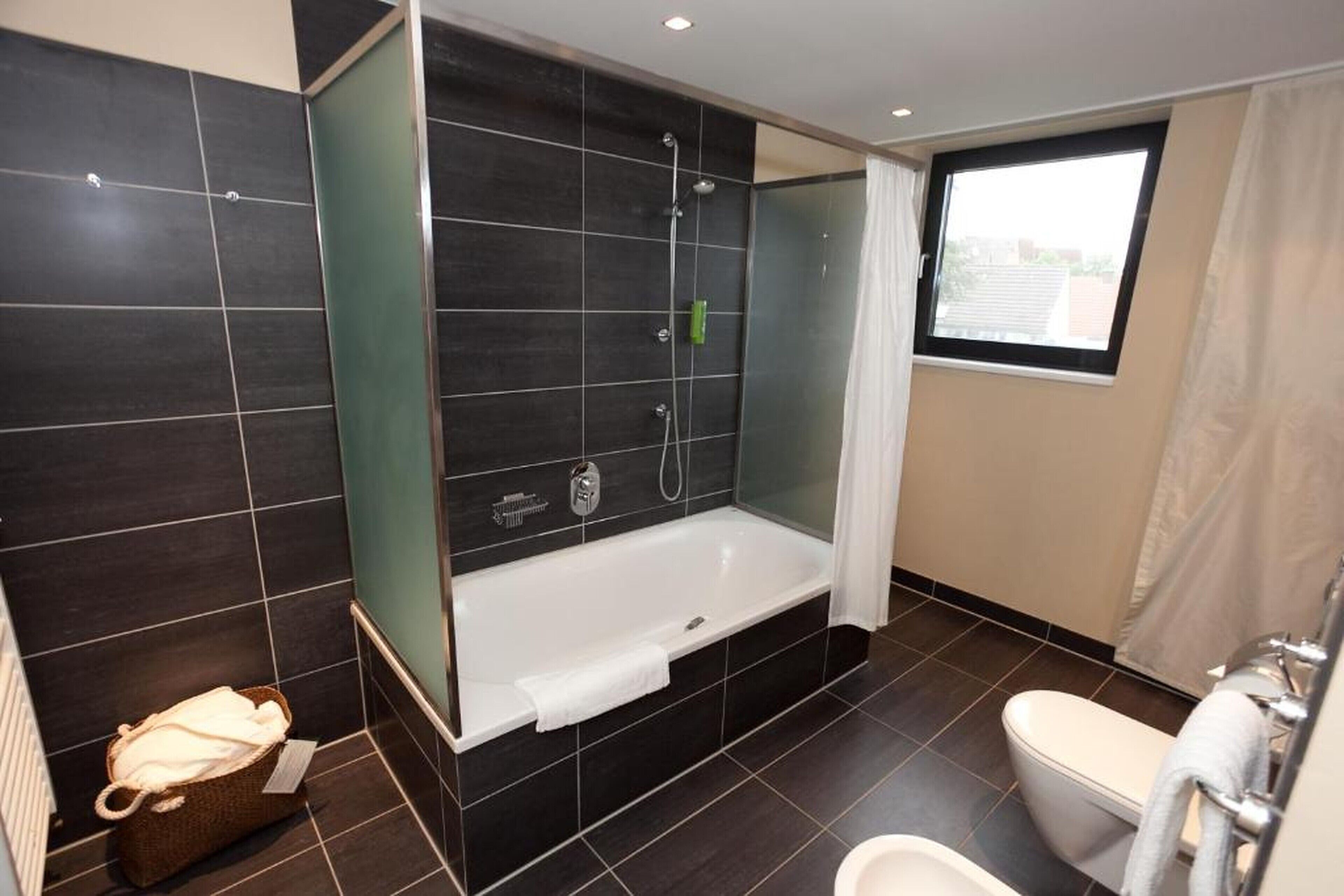 Une salle de bain moderne équipée d’une baignoire, de toilettes et d’un espace douche.