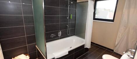 A modern bathroom with a bathtub, toilet, and shower area.
