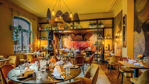 Un restaurant avec des tables rondes, des chaises et des plantes suspendues.