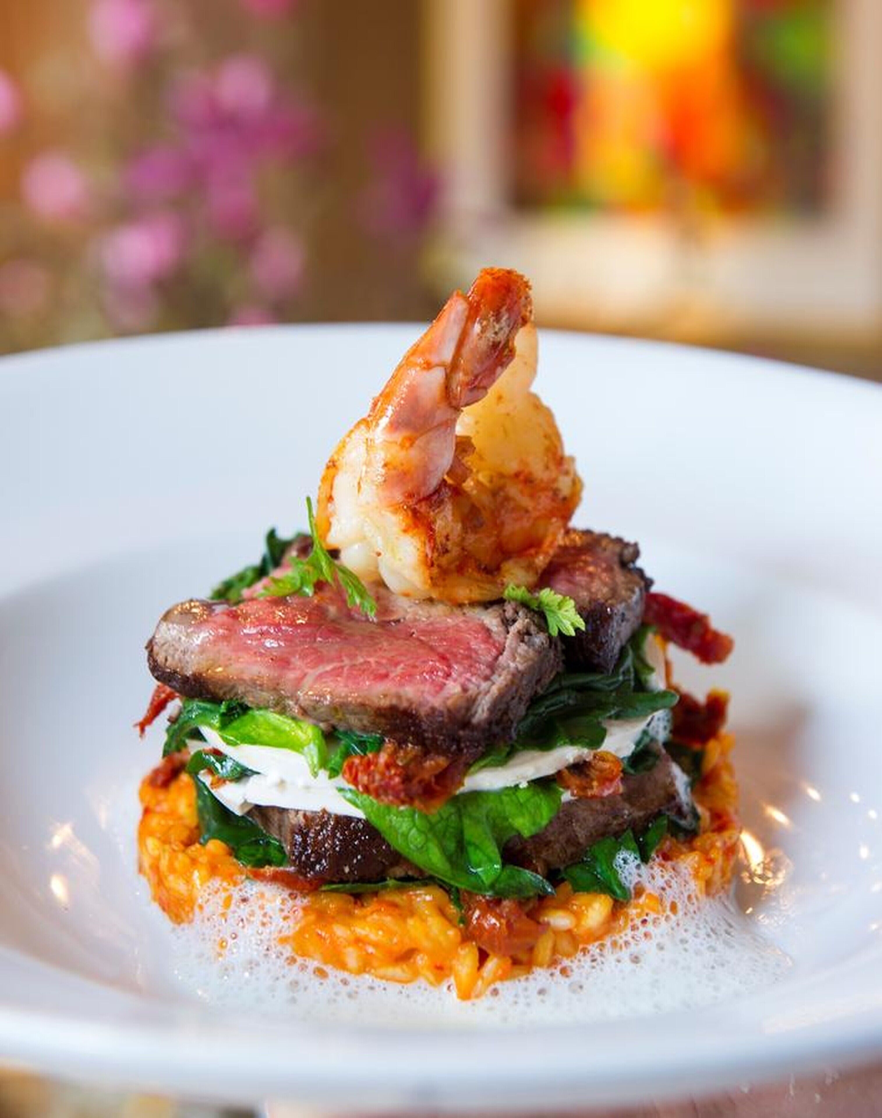 Un plato con carne, camarones y verduras verdes.