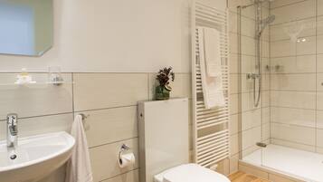 A modern bathroom with a sink, toilet, and glass-enclosed shower.