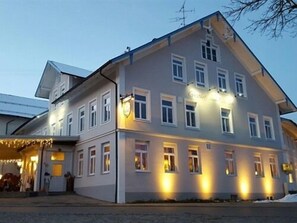 A two-story building with multiple windows, a sign indicating a restaurant, and a snow-covered ground. - Gasthof zum Hirsch (Gorisried)
