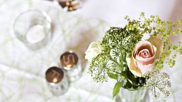 A table setting with a vase of flowers, a glass, and a spoon.